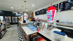 Uma gelataria moderna com diversos doces gelados em exposição, um refrigerador de bebidas e um quadro de cardápio.