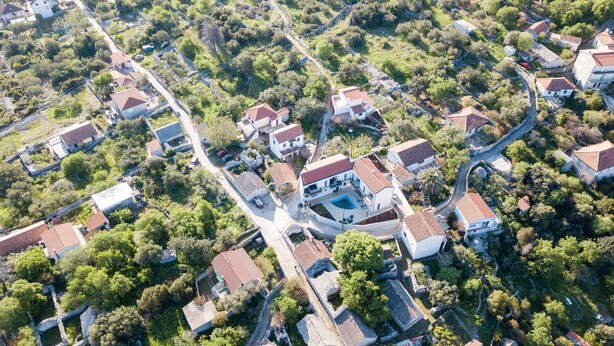Vista aérea de una zona residencial con casas, calles estrechas y abundante vegetación.