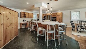 A spacious kitchen with a large island, wooden cabinets, and modern appliances. - MAINE WATERFRONT + MOUNTAIN COMPOUND • SLEEPS 50! (Bridgton)