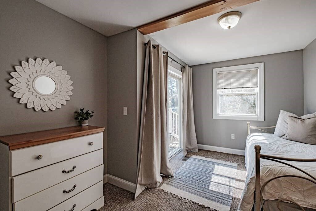 A bedroom with a bed, a dresser, a window, and a ceiling light.