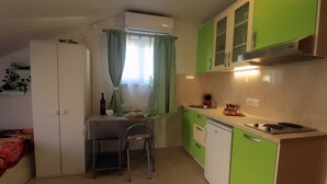 A compact kitchen with green cabinets, a white refrigerator, a dining table with chairs, and a window with curtains. - Apartments Clementina Sunrise - Studio with Balcony (Orebic)