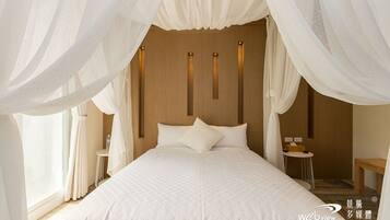 A bedroom with a large bed, white bedding, and sheer curtains.