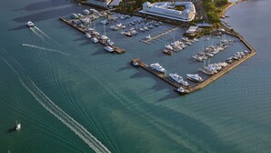 Une vue aérienne d’une marina avec de nombreux quais, un grand navire de croisière et un hôtel dont l’immeuble est particulièrement imposant.