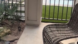 A balcony with a view of a swimming pool, a wicker chair, and a white couch. - Pool/Spa, guesthouse in the heart of ATX (Austin)