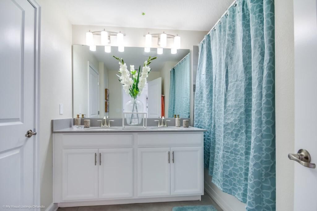 A bathroom with a double vanity, a large mirror, and a shower curtain.
