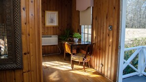 Ein Holzinterieur mit einem Esstisch, Stühlen, einem Blumentopf und einem gerahmten Bild an der Wand.