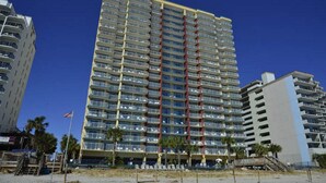 Un grand hôtel avec de nombreux étages, des balcons et un emplacement en bord de mer.