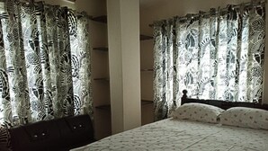 A bedroom with a bed, a nightstand, and zebra-patterned curtains.