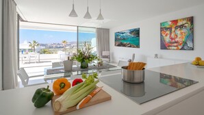 A modern kitchen with a large island, a dining area with a glass table, and a view of the city. - Marbella Golf With Pool Cataleya, Marbella, Spain (Marbella)