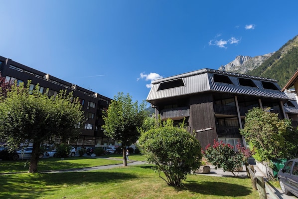 Een gebouw met een balkon, omgeven door bomen en een berg op de achtergrond.