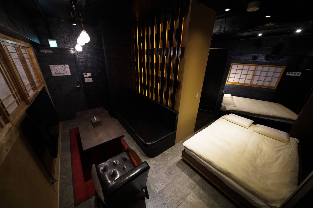 Habitación de hotel pequeña con cama, una mesita, un banco y un panel decorativo en la pared.