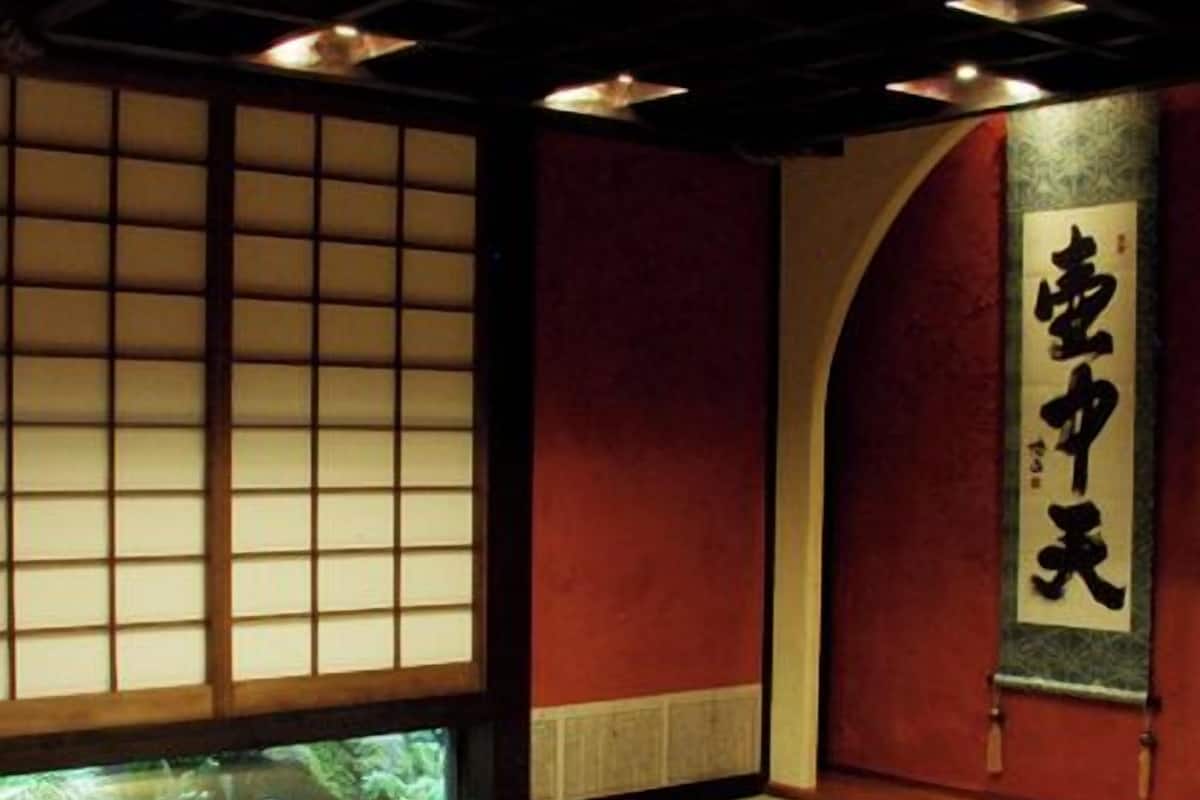 Een traditionele Japanse kamer met tatami vloerbedekking, een verlaagd houten platform en een schuifdeur met kalligrafie.