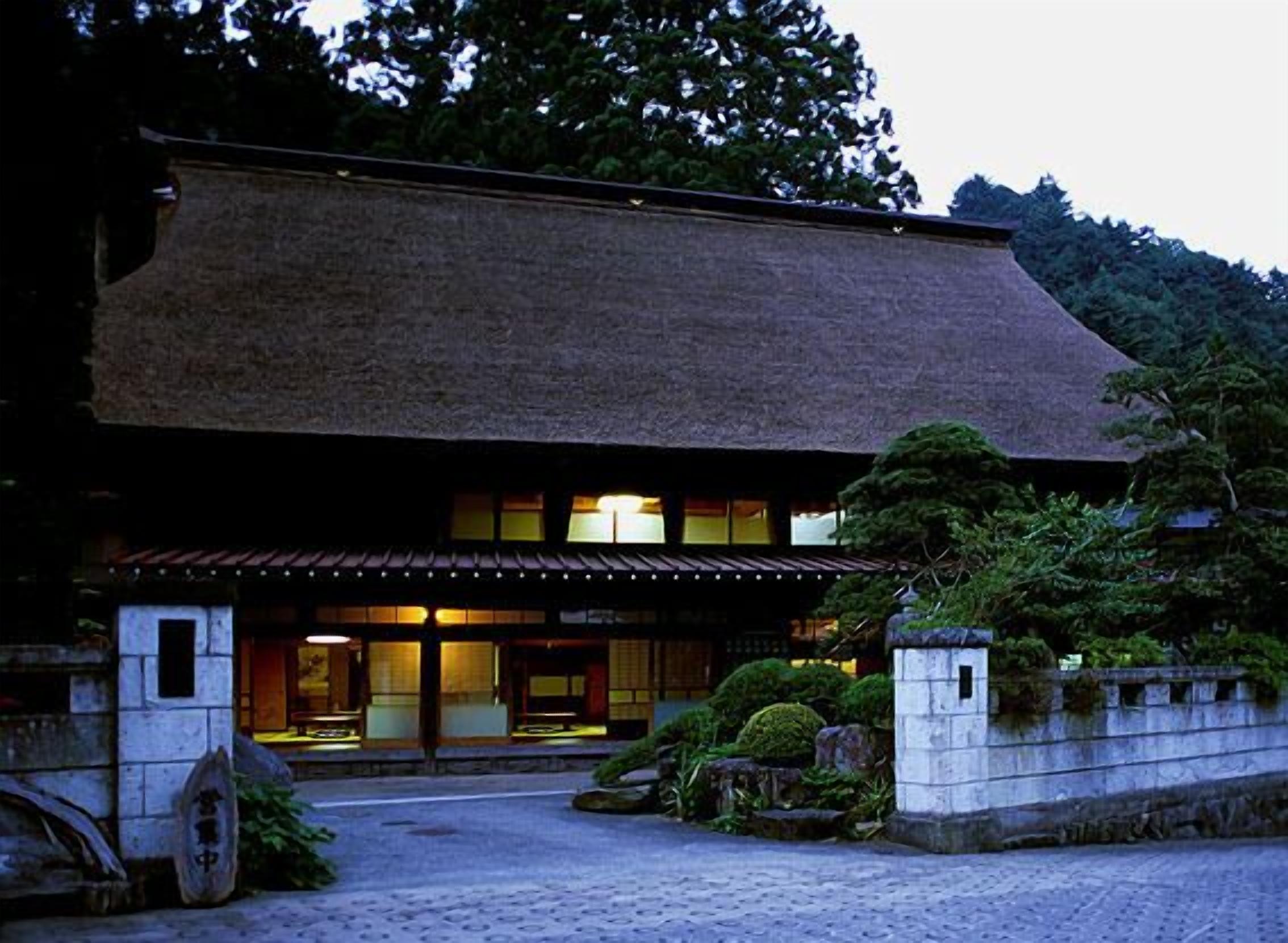 A traditional Japanese building with a tiled roof, a stone entrance, and a well-maintained garden.
