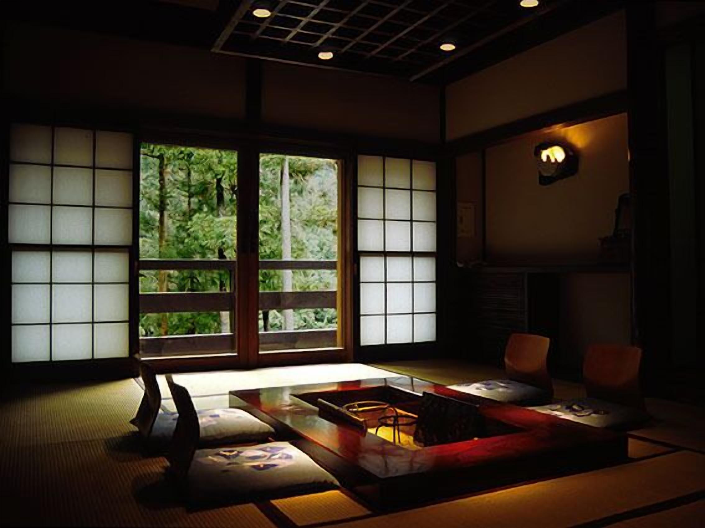 A traditional Japanese room with tatami flooring, a low table, cushions, and a sliding door with a view of greenery.
