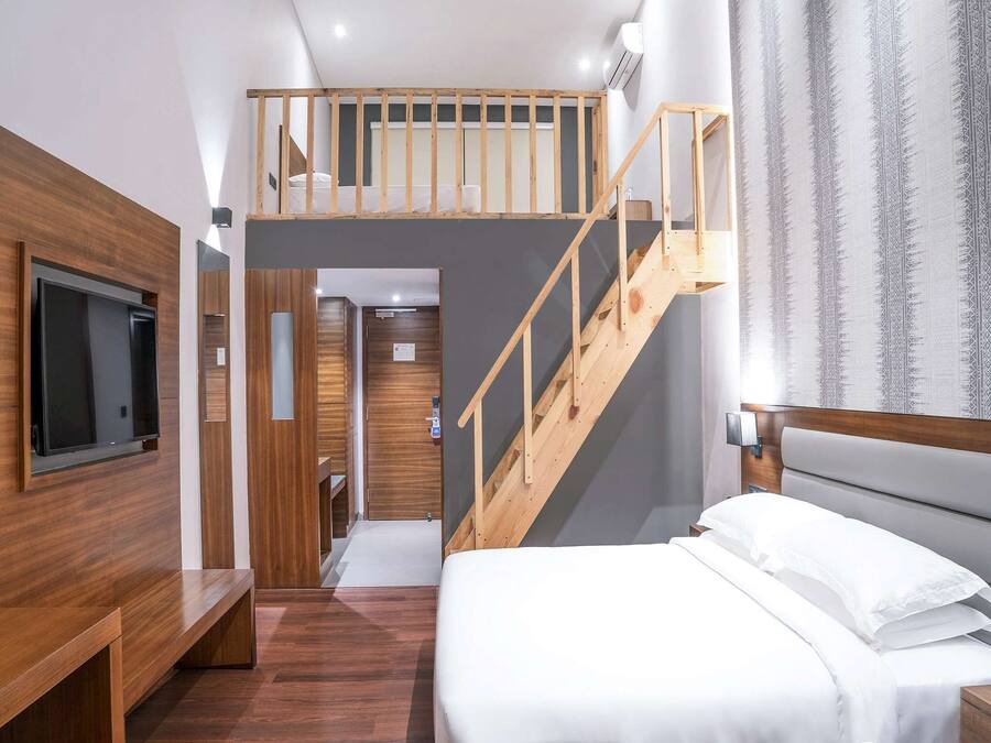 Een moderne hotelkamer met een vide, een houten trap, een flatscreen televisie en een inbouwwachtwoord.