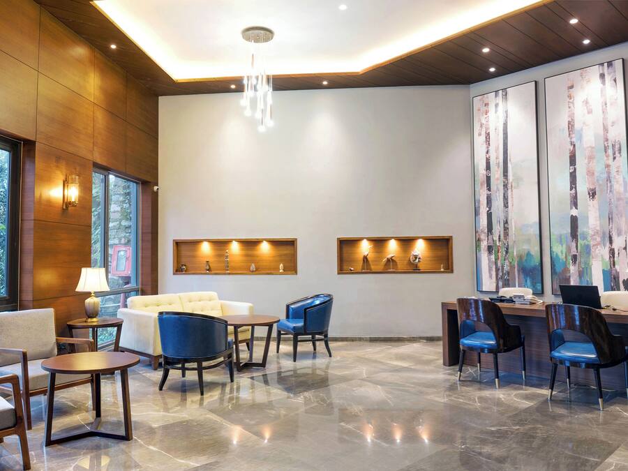 A modern lobby with a reception desk, seating area, and artwork on the walls.