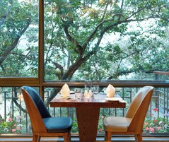 A dining table with two chairs, a glass of water, and a candle.