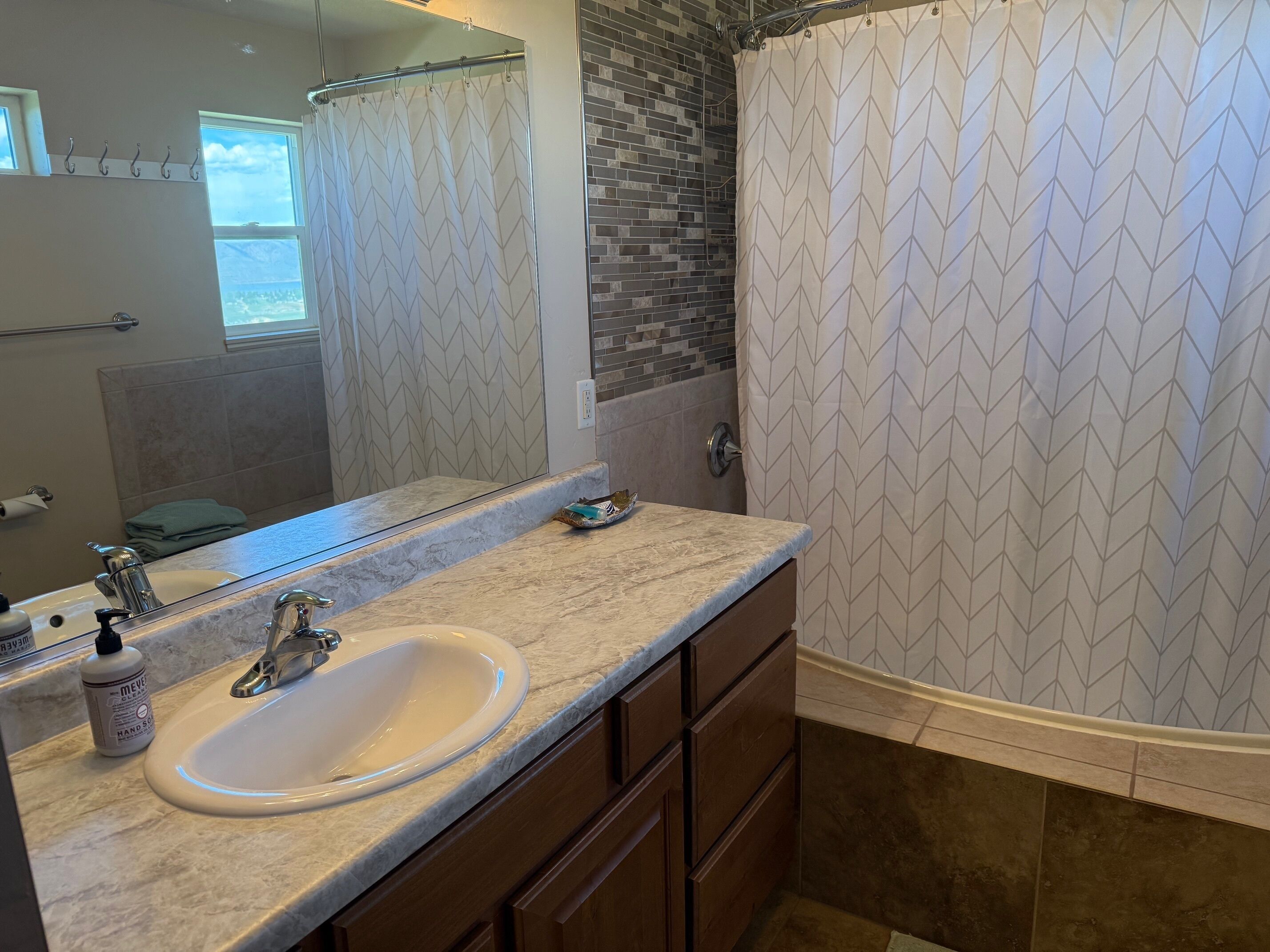 A bathroom with a large mirror, a sink, and a shower curtain.