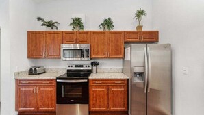 Una cucina con mobili in legno, un frigorifero in acciaio inossidabile, un forno a microonde, un forno e un tostapane.