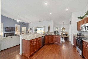 A spacious kitchen with wooden cabinets, a granite countertop, and a dining area with a table and chairs.