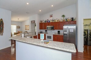 A modern kitchen with granite countertops, wooden cabinets, stainless steel appliances, and a built-in microwave.