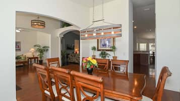 A dining area with a wooden table, chairs, and a hanging light fixture.