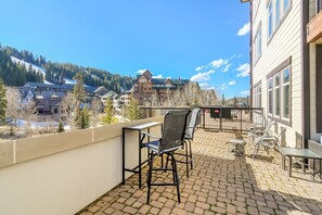 Un balcon avec des sièges d’extérieur, une vue sur une montagne et des bâtiments en arrière-plan.