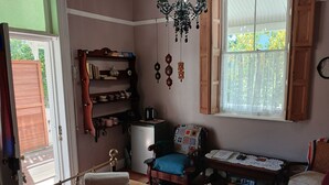 Una habitación acogedora con una cama, una silla, una mesita, una estantería, un refrigerador y una ventana con vistas a la vegetación.