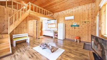 A wooden interior with a staircase, a kitchen area, a seating area, and a television.