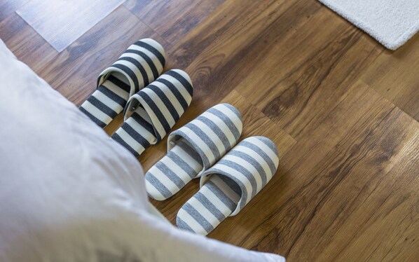 A wooden floor with four striped slippers and a white pillow. - Stone Flower Pension (Sancheong)