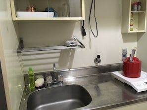 Ein Spülbecken aus Edelstahl mit Armatur, Seifenspender und einer grünen Flasche Geschirrspülmittel.