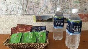Ein Tisch mit einem gewobenen Korb, der Teebeutel, zwei Wasserflaschen und eine Karte im Hintergrund enthält.