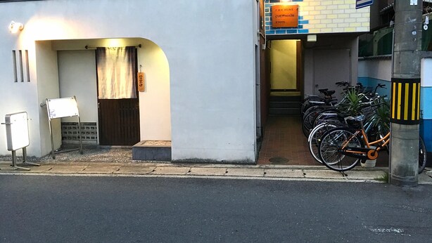 Un edificio con fachada blanca, un letrero que indica una casa de huéspedes y bicicletas estacionadas afuera.