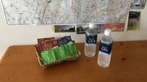 Una mesa con un mapa, una cesta de bolsitas de té y dos botellas de agua.