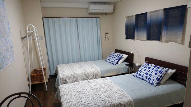 Ein Hotelzimmer mit zwei Betten, einem Heizlüfter, einer Karte an der Wand und einer Klimaanlage.