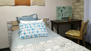 A neatly arranged bedroom with a bed, a bedside table with a book, a chair, and a wall art piece. - I Am Home Guest House 202 (Kyoto)