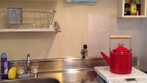 A kitchen with a stainless steel sink, a red kettle on a digital scale, and various kitchen items on the counter. - I Am Home Guest House 202 (Kyoto)