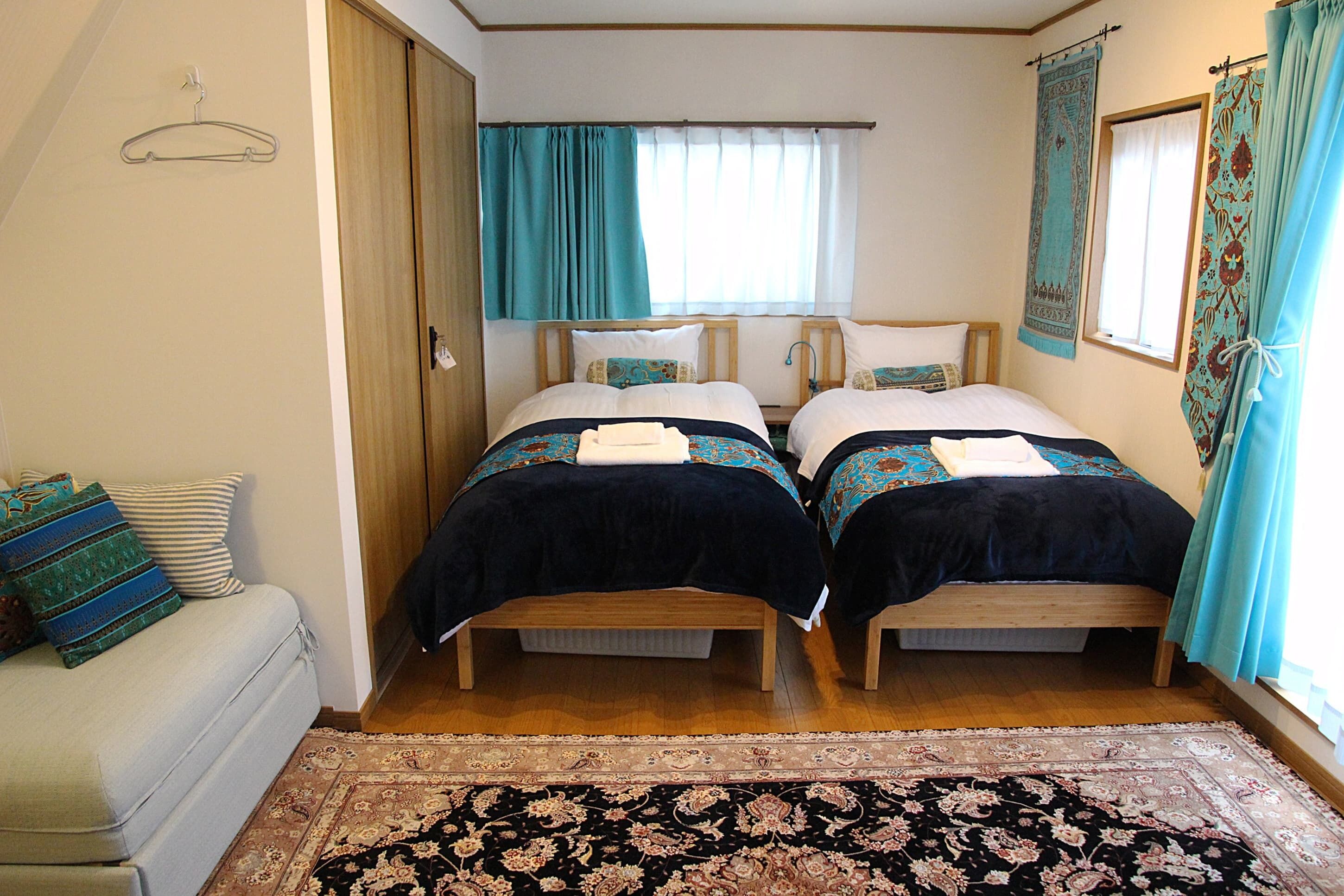 Una habitación con dos camas, un sofá y una alfombra grande.