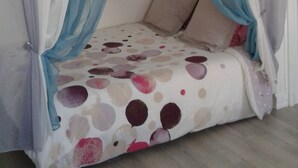 A bedroom with a bed covered by a polka dot bedspread, blue and white curtains, and a wooden floor. - STUDIO by the water with all comfort (Le Havre)