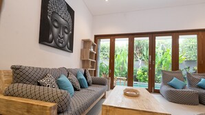 Ein modernes Wohnzimmer mit einem gemusterten Sofa, einem Holztisch und einem großen Buddha-Gemälde an der Wand.