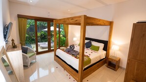 Ein geräumiges Schlafzimmer mit Himmelbett, einem kleinen Nachttisch und Blick auf den Garten durch große Schiebetüren.