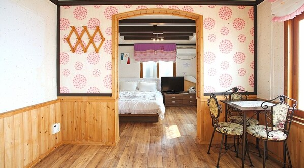 A cozy room with a bed, a desk, and a chair. There is a window with curtains and a wall with a polka dot pattern.