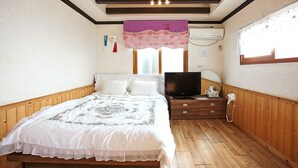 Un dormitorio con una cama de madera, televisor, teléfono y una ventana con cortina.