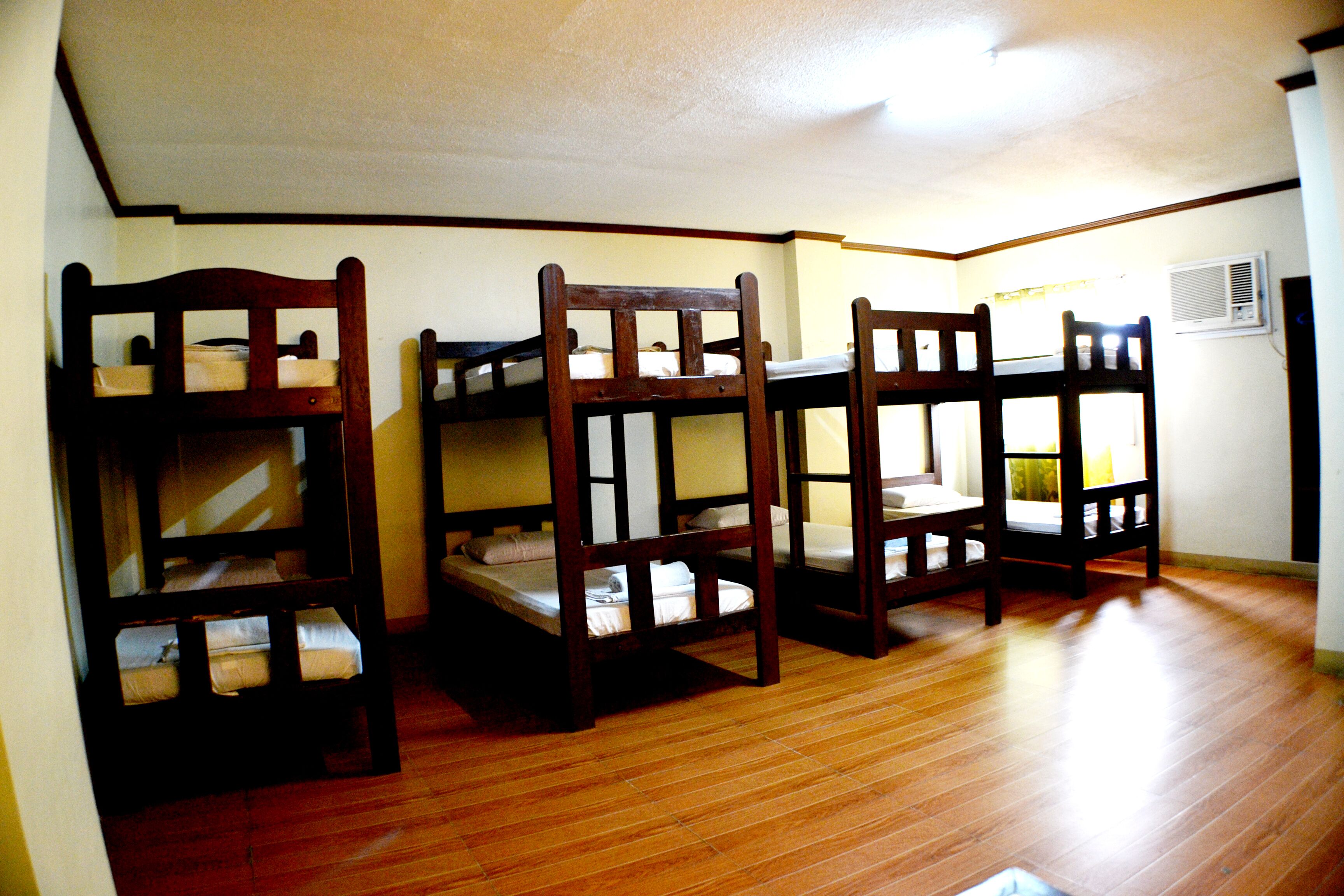 Quarto com beliches e piso de madeira.