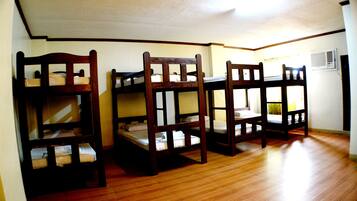 Quarto com beliches e piso de madeira.