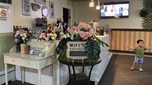 A reception area with a desk, a sign for WIFI password, a TV screen, and a child standing. - Rufina's Leisure Center (Tagum)