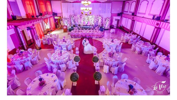 A banquet hall with round tables and chairs, a central stage, and a red carpet. - Rufina's Leisure Center (Tagum)
