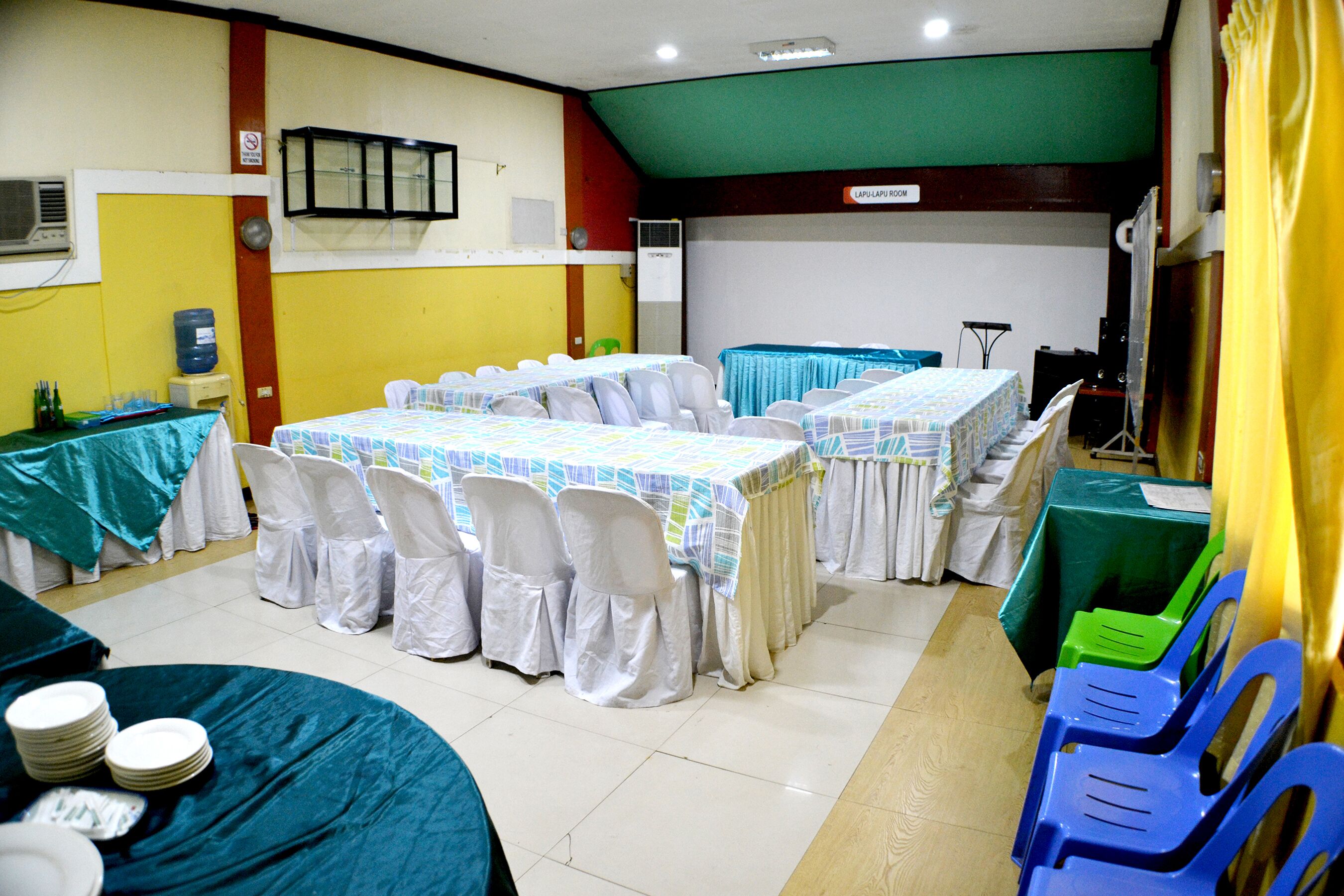 A conference room with tables and chairs, a projector, and a water cooler.