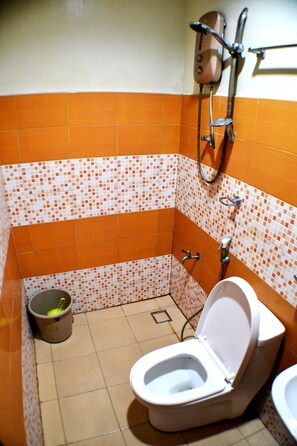 A small bathroom with a toilet, a shower, and a bucket.