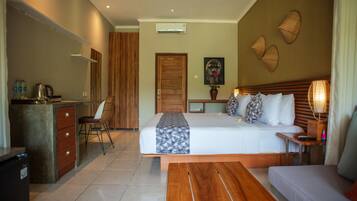 Habitación de hotel con cama, sofá, escritorio con silla, kitchenette pequeña y baño.